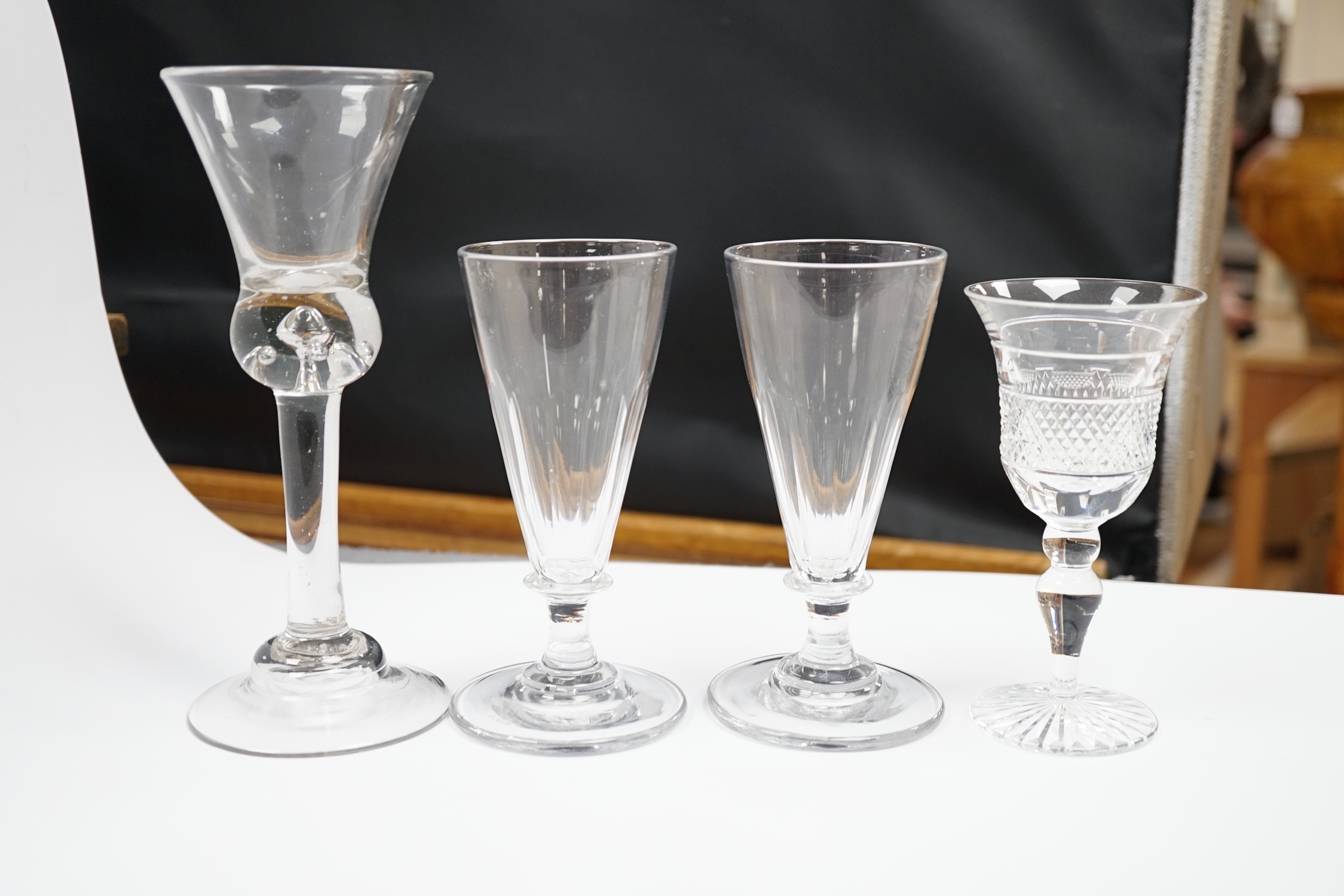 A pair of early 19th century dwarf ale glasses with fluted conical bowls, bladed knop stems and polished pontils, together with a mid-18th century thistle bowl glass with multiple air tears, plain stem and domed foot and